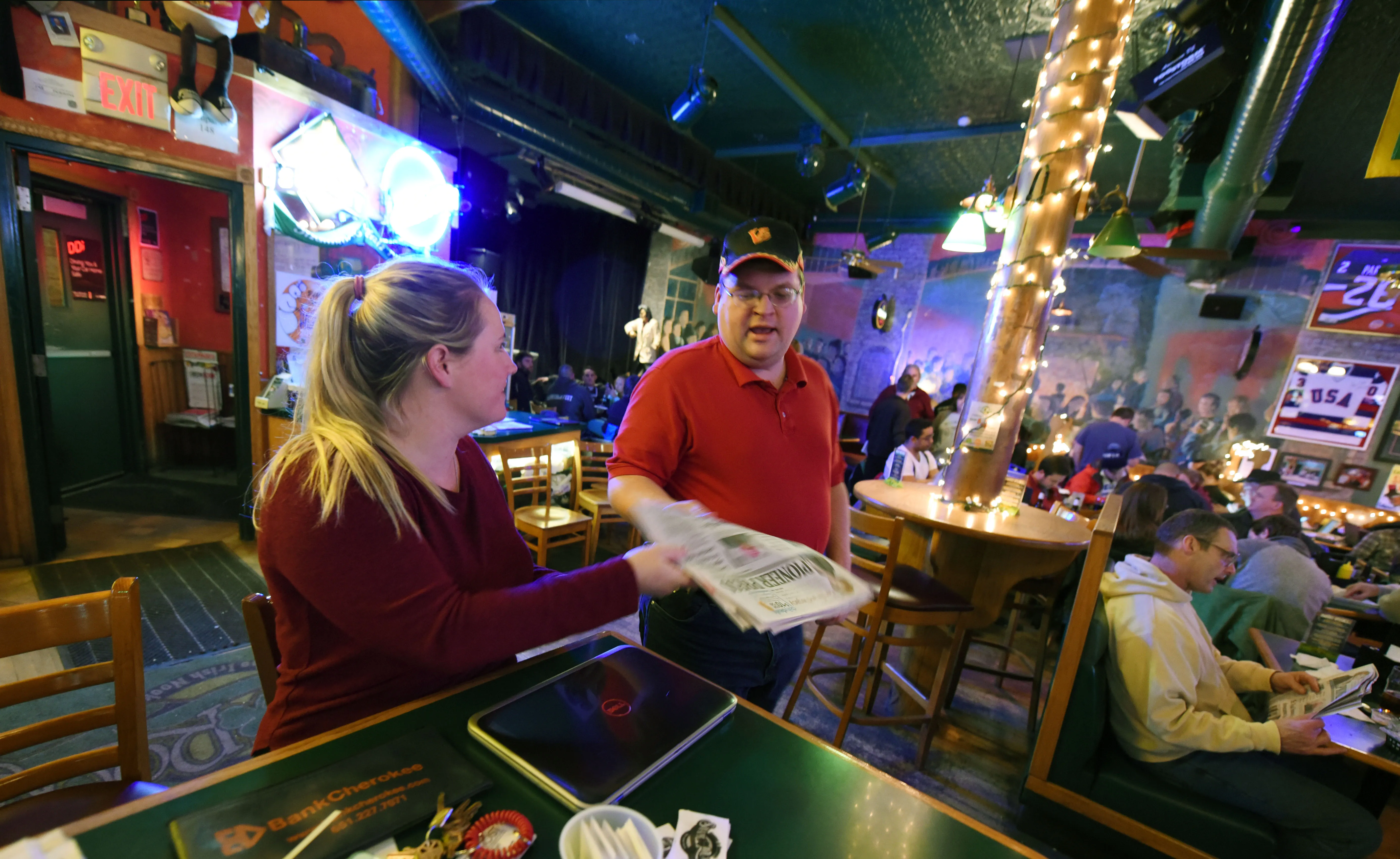 Night manager Katie Schille hands an early edition of the Pioneer Press to treasure hunter Jason Michaelson inside Shamrocks bar and grill in St. Paul, Minn., Wednesday, Jan. 25, 2017. (Pioneer Press: Dave Orrick)