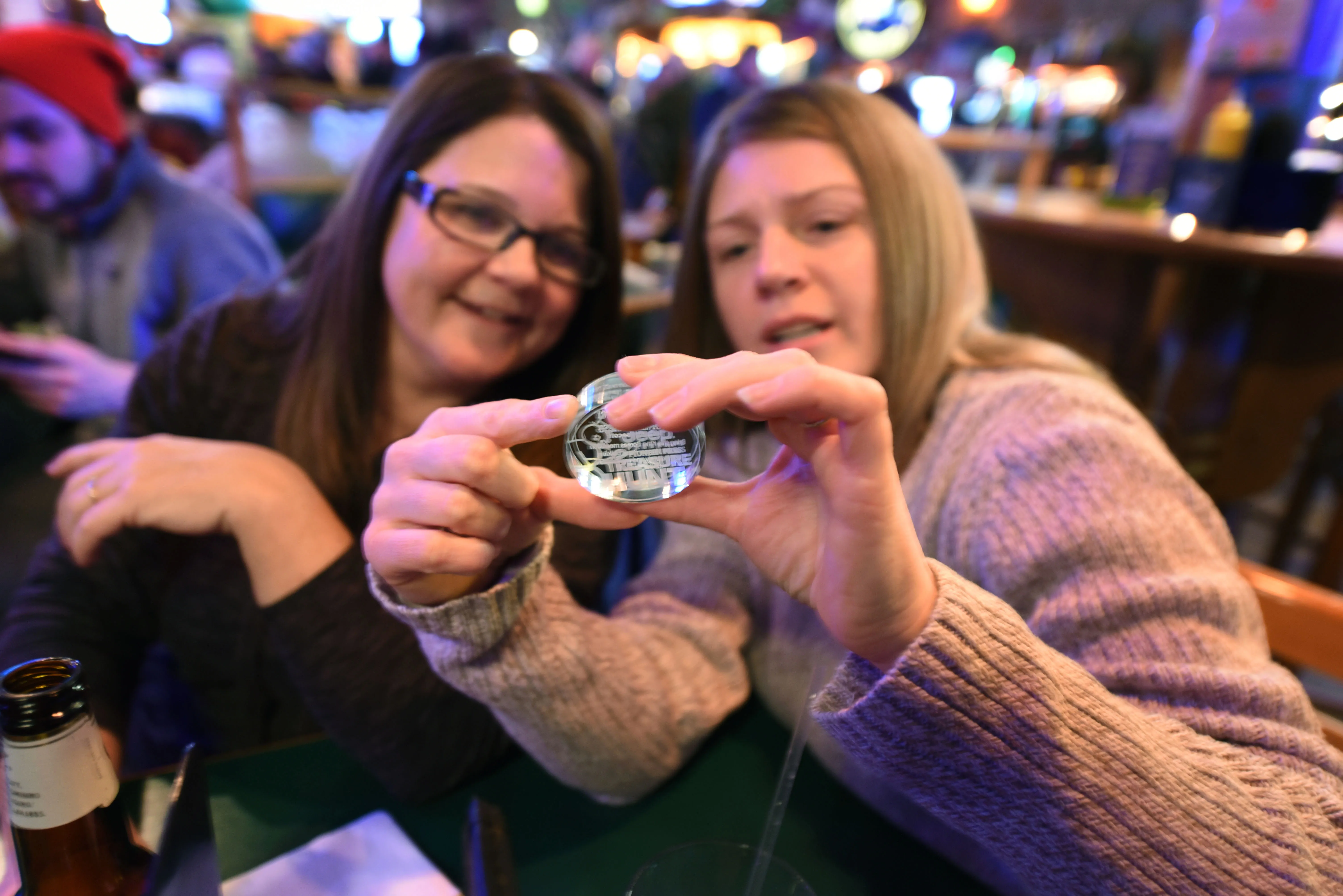 Treasure hunters Sue Segl, left, and Kim Mourning examine a previous Treasure Hunt medallion that Segl won in a drawing earlier last year on Wednesday, Jan. 25, 2017, inside Shamrocks bar and grill in St. Paul, Minn. (Pioneer Press: Dave Orrick)