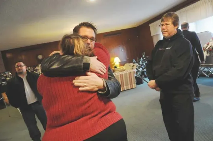 Nicole Evenson, center, gets a hug from Cooler Crew member, Randy Rust, who’s with other Cooler Crew members, Ken Ng, left, and Mike McMahon, right, before the funeral of her husband, Mark Evenson, January 8, 2010, at Gustavus Adolphus Lutheran Church, St. Paul. (Pioneer Press: Jean Pieri)