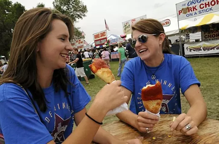 Alexis Friesen, left, and Jenny Asturias, both of Lakeville, munched on their stuffed pizza on a stick at the Taste of Minnesota at Harriet Island in St. Paul. Taste of Minnesota, like many other regional festivals, has gone through ups and downs over the years and hopes to resurface next year after a three-year absence. (Pioneer Press 2009 file: Scott Takushi)