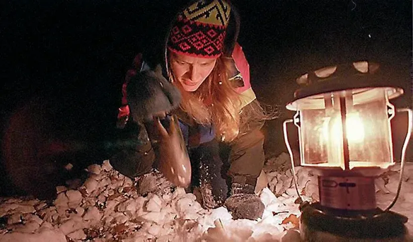 A hunter searches by lantern light