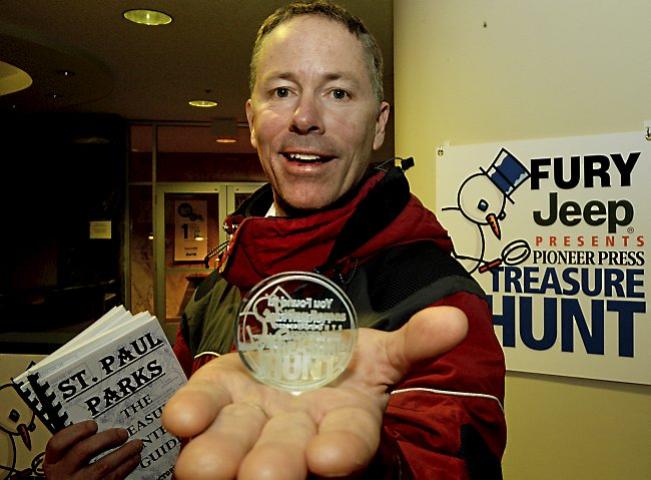 Steve Worthman shows off the Pioneer Press Treasure Hunt medallion after finding it Thursday, Jan. 22, 2015, at Snail Lake Regional Park in Shoreview. He's also holding copies of his book "St. Paul Parks: The Treasure Hunter's Guide." (Pioneer Press: John Autey)