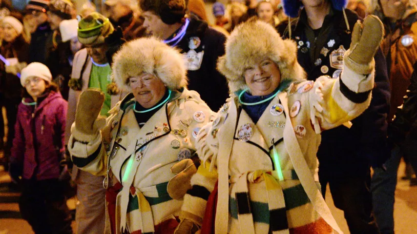 Twin sisters Joan Kelly, left, and Jane Lonergan wave to people on the sidewalks as the pair march in the Winter Carnival Moon Glow Parade in St. Paul on Thursday, Jan. 28, 2016. (Pioneer Press: John Autey)