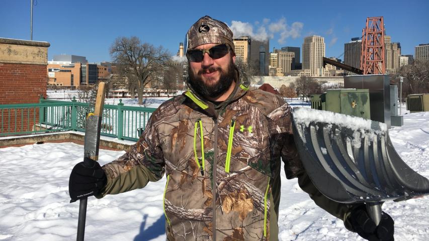 Paul Antinozzi of Ham Lake shows his homemade medallion digger, at left — a broom/steel brush combo he used as a professional caulker that he says is perfect for the hunt. (His head-to-toe camo totally did not work, though, in the glare of Wednesday’s new snow.) (Lisa Legge / Pioneer Press)