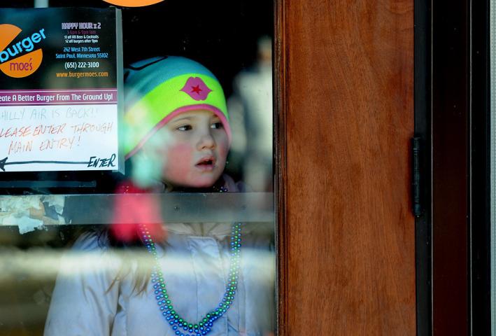 A girl watched the Winter Carnival Grande Day Parade from inside the doorway of burger moe's on West Seventh Street in St. Paul, Saturday January 25, 2014. (Pioneer Press: Jean Pieri)