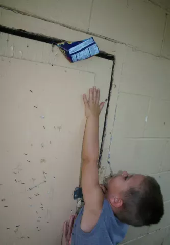 The Heimatfest medallion was in a popcorn box, tucked above the service door at the warming house in Lagoon Park. Isaac Schueller demonstrates. PHOTO BY MATHIAS BADEN