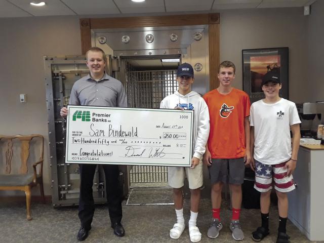 Premier Bank of Osseo presents the $250 check to the winner of the Osseo Lions Roar medallion hunt, sponsored by Premier Bank. Pictured on the left from Premier Bank is Dan White. Holding the check on the right is the finder Sam Bindewald of Osseo. Also picture is the rest of his search team, Matthew Holien of Brooklyn Park and Carson Streich of Brooklyn Park. The medallion was found under a bleacher seat in Sipe Park. The team searched for about half an hour. They left for a while and came back searched so
