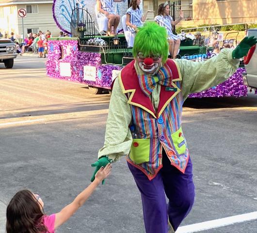 A clown shakes hands with a young parade-goer.