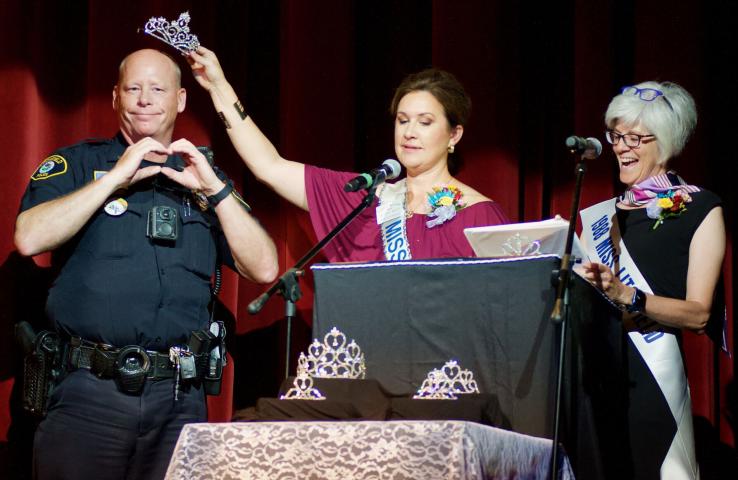 Emcee Megan Yates playfully holds a crown over Watercade grand marshal Gary Gruenke’s head as emcee Shauna Hannan laughs during the coronation July 10.