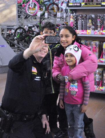 Litchfield Police Officer Gary Gruenke pauses to take a photo with children who were participating in the Shop with a Cop event in December 2015.