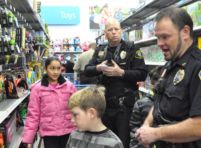 Litchfield Police Officers Gary Gruenke, left, and Ben Aho, right, help kids at the Shop with a Cop event decide what to buy for Christmas presents. Needy families are able to spend $75 to buy Christmas gifts for themselves and family. File photo.