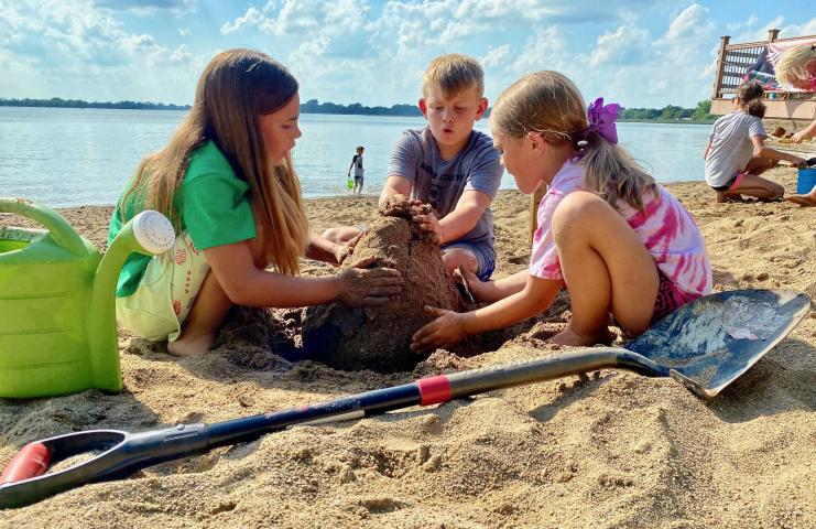Adriana Wagner, 10, Owen Wagner, 9, and Aaliyah Swanson, 7, work on their sand sculpture Friday afternoon. The trio said they planned to build a volcano with a house, hoping to repeat their sculpture success of one year earlier when they took third place in the contest.