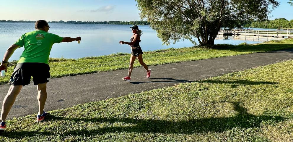 Jim Watt reaches a cup of water toward one of the field of 85 runners in Saturday's 4-mile run.
