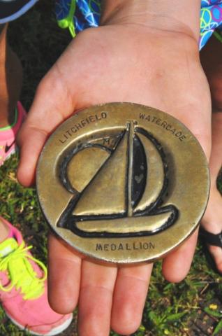 Sydney McCann holds the Watercade medallion, which she unearthed from a thicket of pine trees in the shadow of Litchfield's water tower.