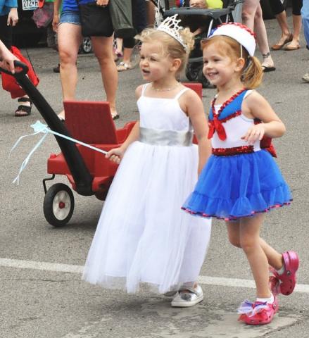 4-year-olds Elise Carlson, left, and Morgan Johnson hold hands during the Watercade kiddie parade Saturday morning.