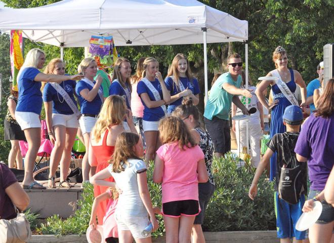 Miss Litchfield candidates gather on stage during KLFD's beach party Friday night, as KLFD intern Josh Spreiter throws flying discs to children. Pictured are, from left to right, candidates Madison Westphal, Ali Richardson, Alana Caron, Alyssa Raiber, Emily Schreiber and Erika Hart, Spreiter and Litchfield princess Paige Dilley. Not pictured is candidate Riley Anderson.