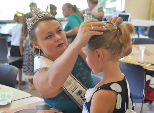 Watercade Princess Autumn Raiber fixes Elsa Helstrom's crown at the Prince and Princess for a Day event July 6.