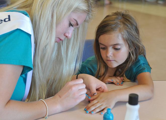 Sloan Quin, right, watches intently as Watercade candidate Shelbie Behnke paints her nails turquoise.