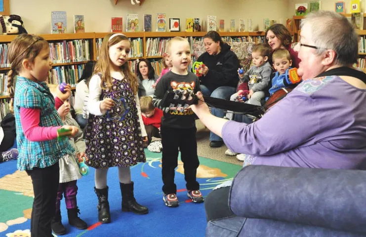 Children dance and shake musical instruments as Jan Pease, this year’s Watercade grand marshal, plays the guitar during Toddler Time in 2014. Children dancing on the carpet, from left, are Brie Finneseth, 4; Madelyn Johnson, 21 months; Emma Wuotila, 5; and William Wendroth, 4.