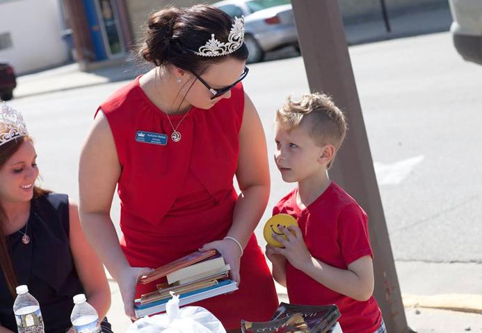 Miss Litchfield Karly Nelson, left, looks on as Litchfield Princess Autumn Raiber, center, collects books and chats with Jack Wendlandt.