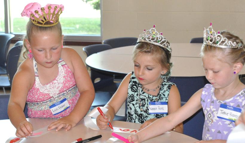 From left — Luci Ficker, 7, Natalie Ross, 7, and Tattrie Ficker, 5, decorated and personalized sashes at “Prince &amp; Princess For a Day” July 6.