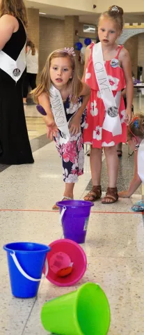 Addison Minton tries to toss a bean bag into a bucket as Olive Caron looks on during the games portion of Prince and Princess for a Day.