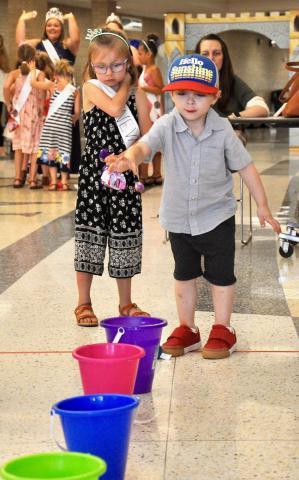 Four-year-old Porter Crusoe improvises the bean bag toss by trying to drop a rubber ball into a bucket.