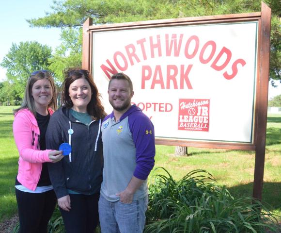 Rachel Smith, Brittany Stoufer and Dany Stoufer hold up the 2019 Hutchinson Jaycee Water Carnival medallion near the Northwoods Park sign. They found the medallion Tuesday, nestled in the daylilies beneath the sign.  Staff photo by Stephen Wiblemo