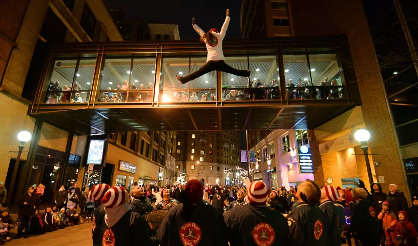 A St. Paul Bouncing Girl waves to the parade-goers in a skyway over 5th Street during the 2015 St. Paul Winter Carnival 2015 Vulcan Victory Torchlight Parade on Saturday, January 31, 2015. (Pioneer Press: John Autey)