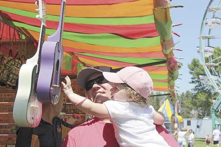 Oakdale resident Dave Gilbert gives his 2-year-old daughter Vayda a lift so she can check out some musical instruments at Hugo Good Neighbor Days Saturday, June 8.  Shannon Granholm | Press Publications