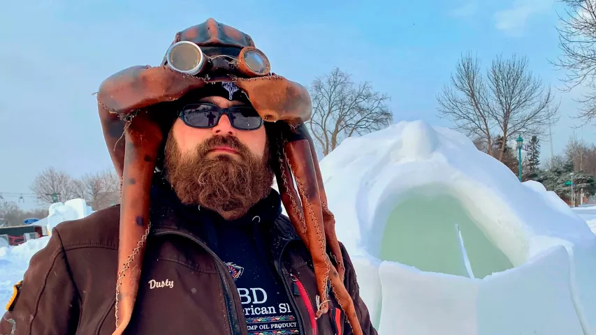 In this Jan 28, 2019 photo, Dusty Thune poses next to his winning snow sculpture “Turtle Island” at Vulcan Snow Park on the Minnesota State Fairgrounds in Falcon Heights, Minn. The sculpture prompted organizers to clarify rules on sculpture subjects, prohibiting anything that was controversial or not family friendly. The artists submitted two proposals this year but were denied because they were inappropriate or political, including another one depicting Trump. (AP Photo/Jeff Baenen)