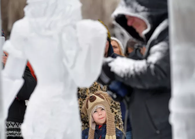 Oliver Pohlen, 6, from Hopkins watches as an ice sculpture artist puts the finishing touches on his creation in Rice Park before the 2020 St. Paul Winter Carnival King Boreas Grand Day Parade in downtown St. Paul on Saturday, Jan. 25, 2020. (John Autey / Pioneer Press)