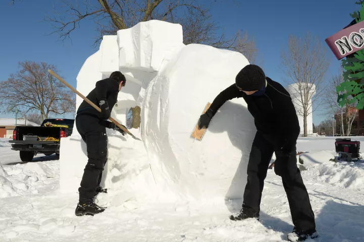 John Baller, right, and his son Josh of Stillwater carve "Back to the Moon" out of snow at the Minnesota State Fairgrounds in Falcon Heights, Sunday, Jan. 24, 2021. The sculpture features the Man in the Moon with a rocketship hitting him in the nose. This year's St. Paul Winter Carnival event is not a competition as in other years, due to it being a paid drive-through event open to paying vehicles only, each day from January 28th February 7th. (Scott Takushi / Pioneer Press)