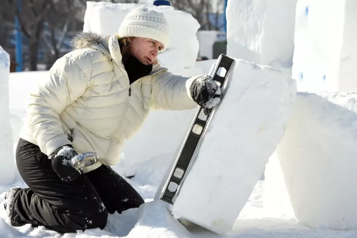 Shauna Ruthenbeck of Shakopee checks to make sure that her block of snow is even, as teams work on their snow and ice sculpture at the Minnesota State Fairgrounds in Falcon Heights, Sunday, Jan. 24, 2021. Ruthenbeck's team consisted of her son Nathan and daughter-in law Nicole Sadowski. They are carving a large snow sculpture titled " You Shall Not Pass!" with figures of Gandalf and the Balrog, from Tolkien's "The Lord of the Rings." This year's St. Paul Winter Carnival event is not a competition as in othe