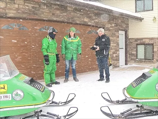 Roger Kram and his son Wyatt are pictured with WDAY-TV News reporter Kevin Wallevand. The father-and-son duo will be driving their 1973 John Deere snowmobiles to re-create the International 500 Snowmobile Race from Winnipeg, Manitoba, to the Twin Cities. (Forum News Service)