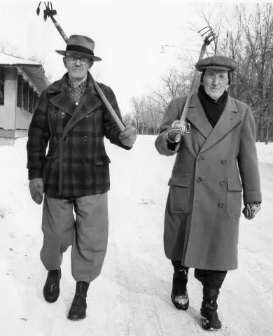 Armed with garden tools, Charles Shafer, left, and Ole Strand, both of St. Paul, walk down a snow-covered road in Como Park on their way to search for the Pioneer Press Treasure Hunt Medallion during the 1955 St. Paul Winter Carnival. (Pioneer Press file photo)
