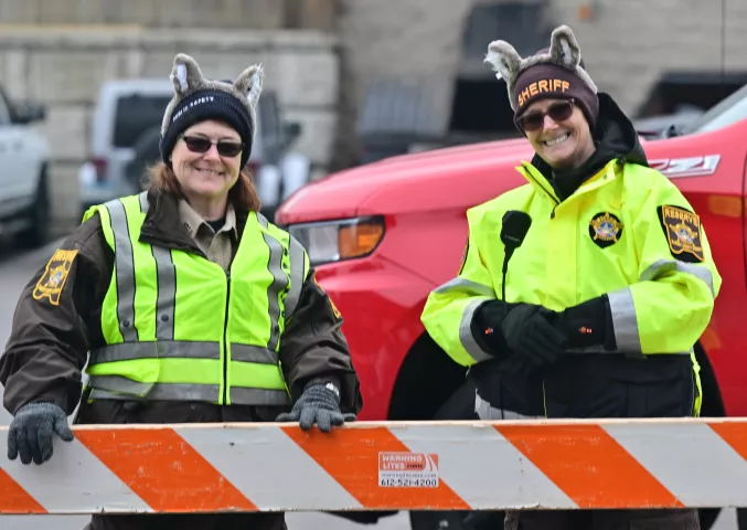 Ramsey County Reserve Sheriff Deputies Kathie Strong, left and Kathy Smith man a barricade with smiles during the 2024 St. Paul Winter Carnival King Boreas Grande Day Parade along West 7th Street in downtown on Saturday, Jan. 27, 2024. (John Autey / Pioneer Press)