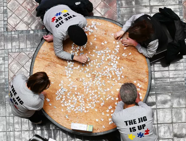 A team wears matching shirts stating “The Jig Is Up” while working on a puzzle at the 2023 Winter Carnival Jigsaw Puzzle Contest at Landmark Center in St. Paul on Saturday, Jan. 28, 2023. (John Autey / Pioneer Press)
