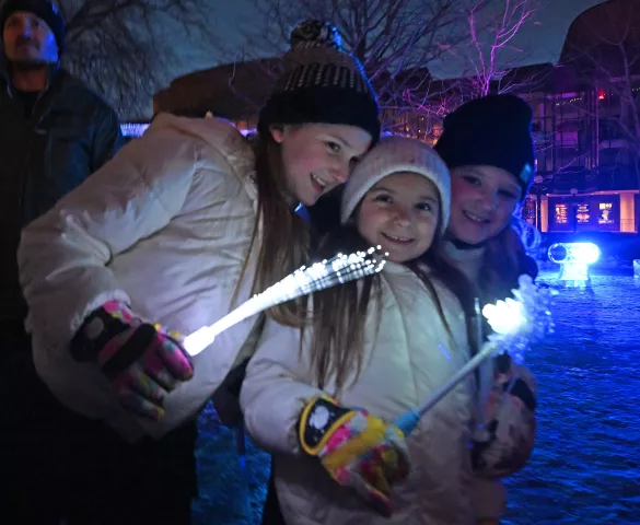 (l-r) Sisters Charlotte, 9, Lu, 6 and Frankke Johnston, all from Blaine, wave their glow wands at Rice Park in St. Paul on Thursday, Jan. 26, 2023. The Royal Family and the Vulcans joined with community members to officially start the 2023 St. Paul Winter Carnival. (John Autey / Pioneer Press)