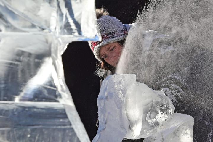 Deneena Hughs from Eden Prairie kicks up a cloud of snow as she carves a block of ice for her teams ice sculpture “You Left the Toilet Seat Up Again” at Rice Park in St. Paul on Friday, Jan. 27, 2023. (John Autey / Pioneer Press)