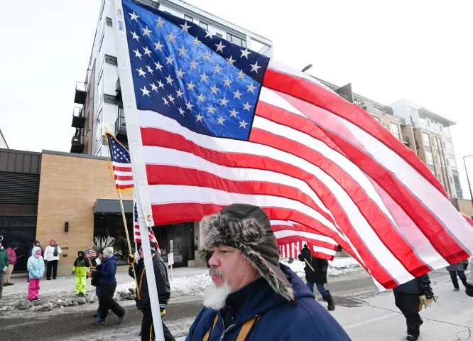 A veteran with the 4th District American Legion carries the American Flag in the 2023 Winter Carnival Grande Day Parade in downtown St. Paul on Saturday, Jan. 28, 2023. (John Autey / Pioneer Press)