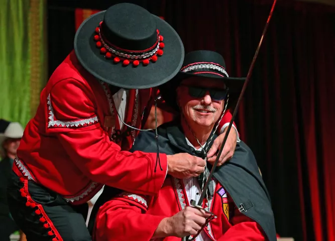Jamie Rued, 2024 Notos, Prince of the South Wind, has his caped pin by outgoing Prince of the South Wind Dennis Boe during the 2024 St. Paul Winter Carnival Royal Coronation at the RiverCentre in St. Paul on Friday, Jan. 26, 2024. (John Autey / Pioneer Press)